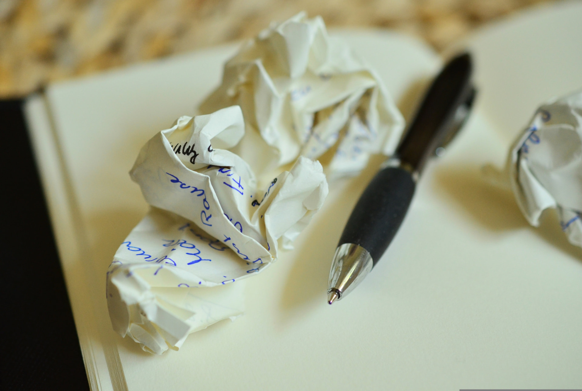 Un stylo posé sur un cahier, à côté de feuilles froissées, pour déposer ses pensées par écrit