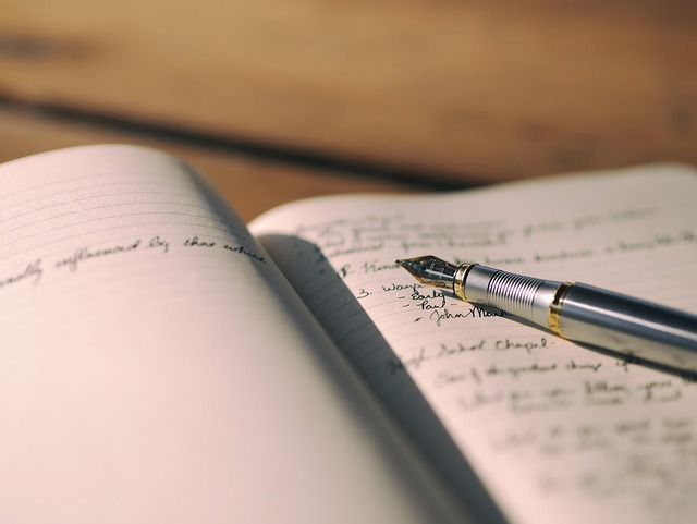 Un carnet ouvert avec des notes manuscrites et un stylo plume posé sur ses pages